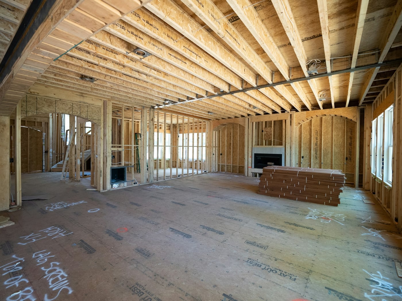 Open main floor framed out on a job site, with engineered joists overhead