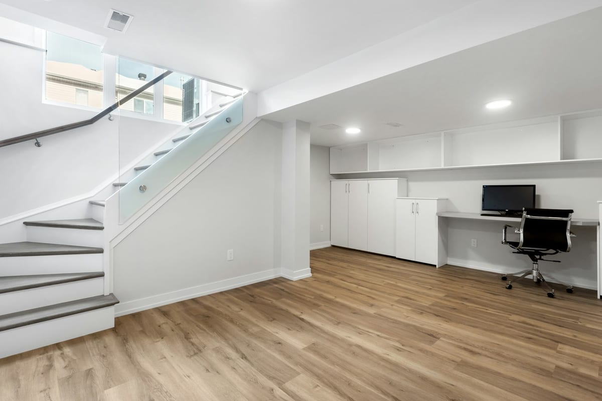 Finished lower-level living space with recessed lighting and built-in cabinetry