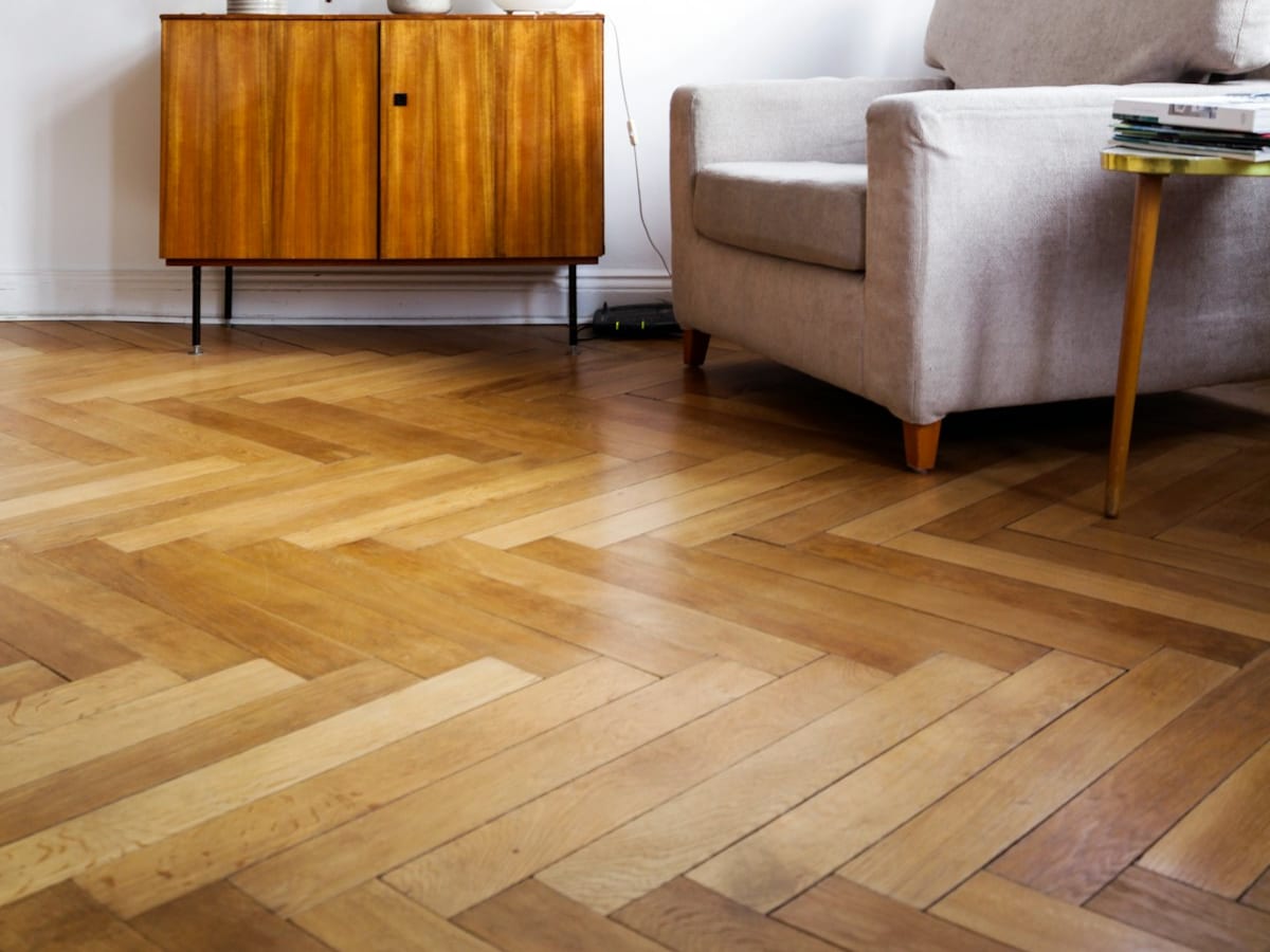 Herringbone oak flooring laid through a living room, running up to the baseboard