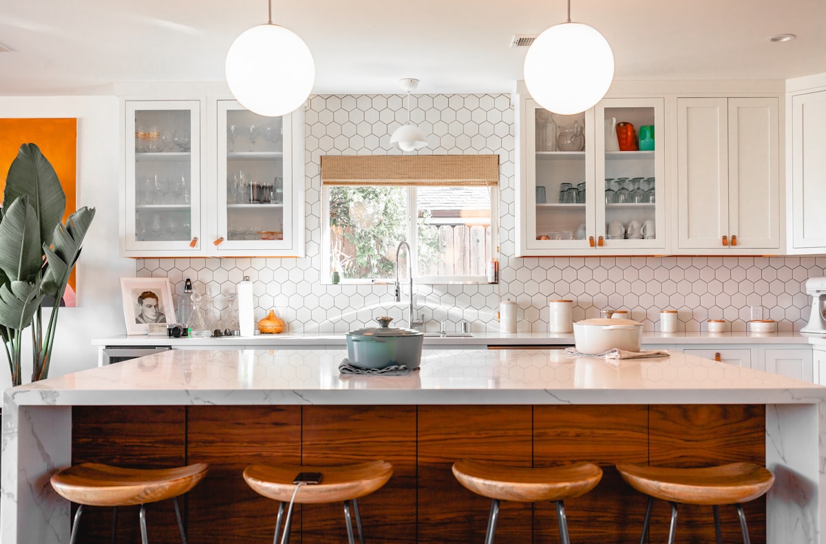 Renovated modern kitchen with dark cabinetry, stone countertops, and pendant lighting